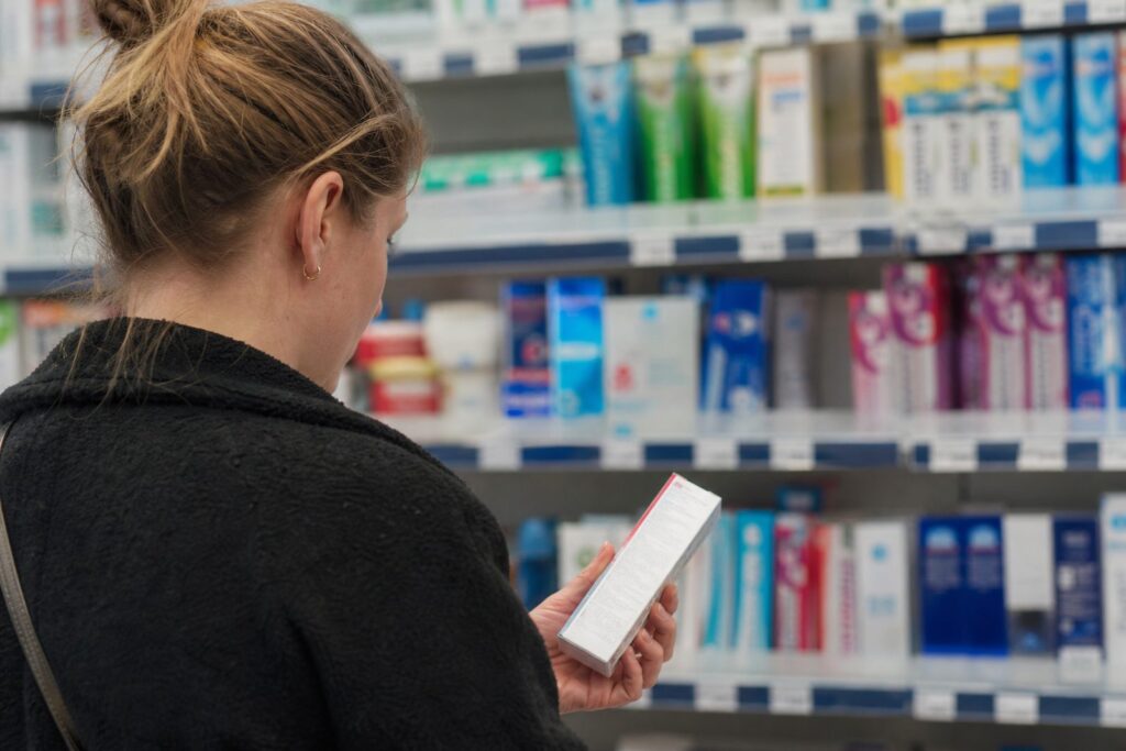 Iemand leest de achterkant van een doosje tandpasta voor het schap in de drogisterij