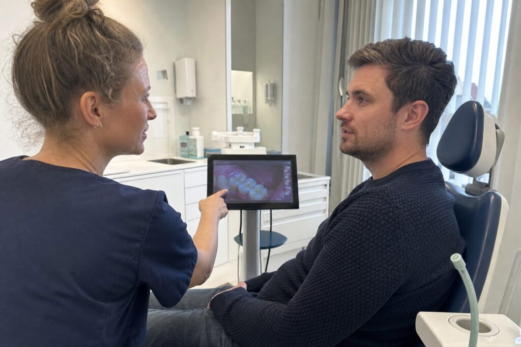 Mondhygienist laat een patient op een scherm het gebit zien